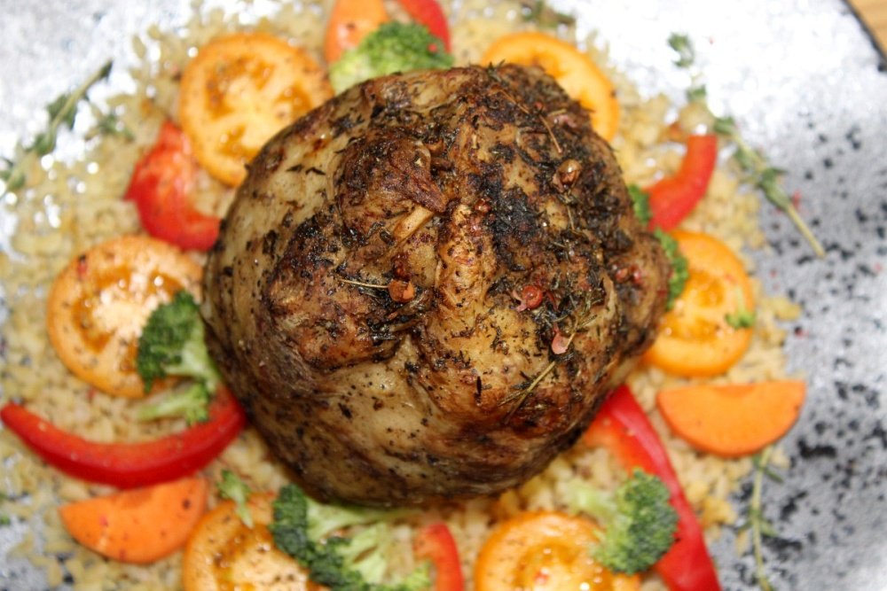 Udekorowany warzywami talerz, na nim upieczony z tymiankiem, ziołami i czosnkiem