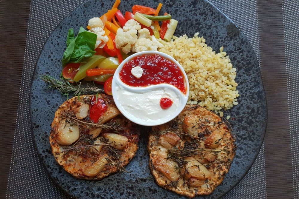 Na talerzu plastry pieczonego z tymiankiem i czoskiem selera podane z kaszą, warzywami i sosami