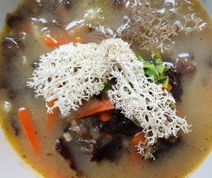 Zdjęcie przedstawia talerz zupy Opieńkowej przystrojonej chrobotkiem reniferowym