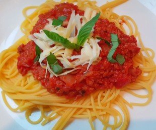 Na zdjęciu talerz, na nim Spaghetti Bolognese podane z tartym serem