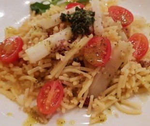 Na zdjęciu talerz, na nim Skorzonera z makaromen, prażonymi orzechami, pesto i pomidorkami koktajlowymi