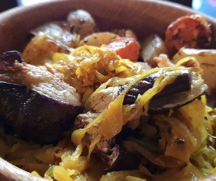 Na zdjęciu drewniana miska wypełniona Kapustą po Indyjsku z bakłażanem podana z pieczonymi ziemniakami