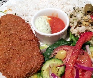 Na zdjęciu talerz, na nim Schabowy z seitana podany z ryżem, surówką, warzywami i sosami