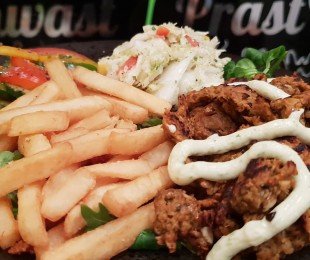 Na zdjęciu talerz, na nim potrawa Seitan Gyros podany z frytkami i sosami