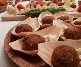 Zdjęcie przedstawia catering, na stole ułożone na talerzykach falafle z sosem majonezowym