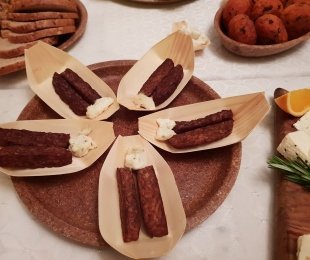 Zdjęcie przedstawia catering, na stole ułożone na talerzykach słupki smazowego tempehu z sosem majonezowym