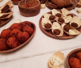 Zdjęcie przedstawia stół z białym obrusem, na stole połmiski z kotletami jaglano pokrzywowymi, falaflami, miseczka z majonezem sojowym