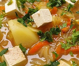 Zdjęcie przedstawia talerz zupy Kapuśniak z kiszonej kapusty z wędzonym tofu