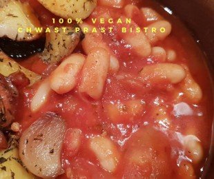 Na zdjęciu drewniana miska, w niej Fasolka po peruwiańsku podana z pieczonymi ziemniakami