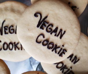 Zdjęcie przedstawia vegańskie ciasteczka z czekoladowym napisem vegan cookie