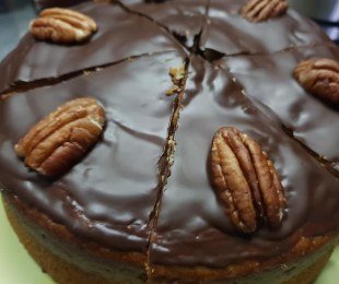 Zdjęcie przedstawia ciasto bananowe z orzechami pekan, polane czekoladą