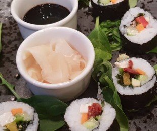Na zdjęciu talerz, na nim potrawa Wegańskie sushi podane z imbirem i sosem sojowym